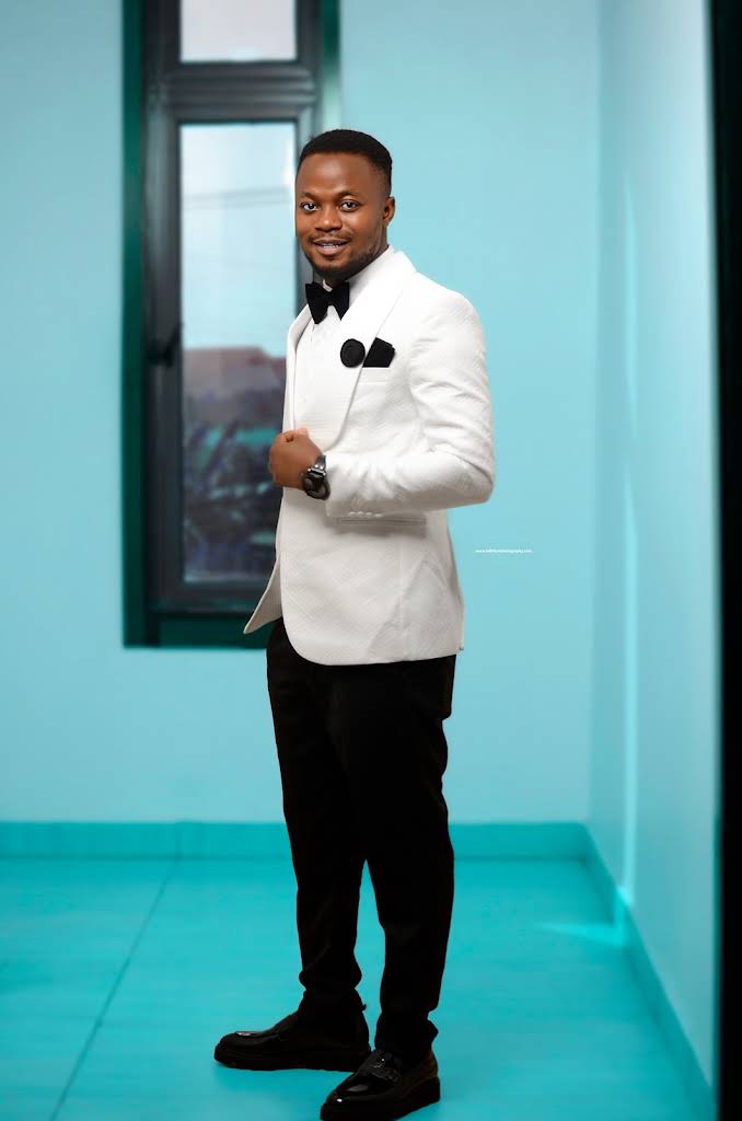 Portrait of a man in a white formal jacket against a teal studio background